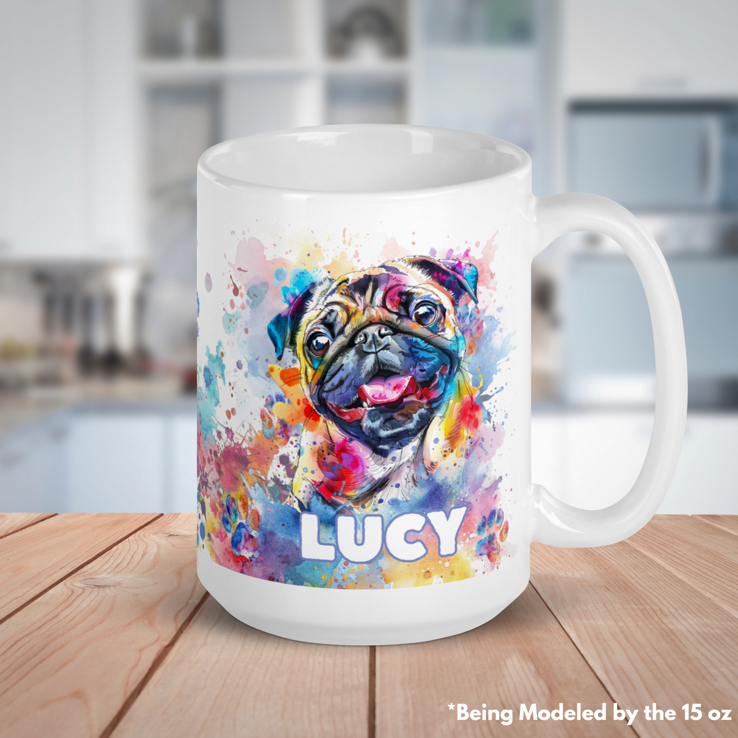 15 oz mug with the custom name of Lucy on it. There are splashes of watercolor, a very cute and happy pug smiling with its tongue out and little watercolor soaked paw prints all over the mug. The base of the mug is white. The coffee, tea, soup cup is sitting on a wooden surface with a blurred white kitchen behind it.