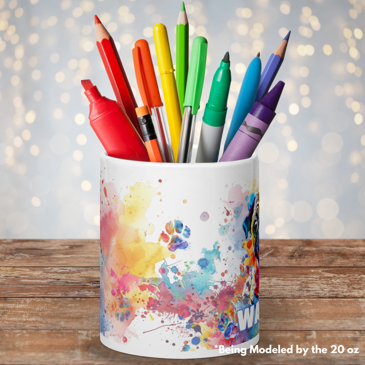 A side view of our 20 oz mug. Mug is being used for a pencil, pen, sharpie, crayon, color pencil, and marker older. The large mug is a great size to hold random items for storage. The mug is on a wooden surface with blurred fairy lights behind.