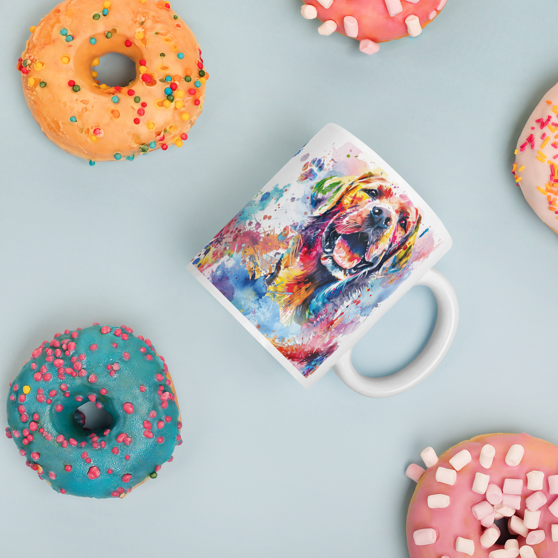 Doggone Proud Lab Dog Mug. A fun colorful mug with handle showing a happy Labrador Retriever dog surrounded by watercolor splashes, clouds, and paws. Mug is laying flat with donuts around it.