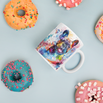 Doggone Proud Frenchie Dog Mug. A fun colorful mug with handle showing a happy French Bulldog surrounded by watercolor splashes, clouds, and paws. Mug is laying flat with donuts around it.