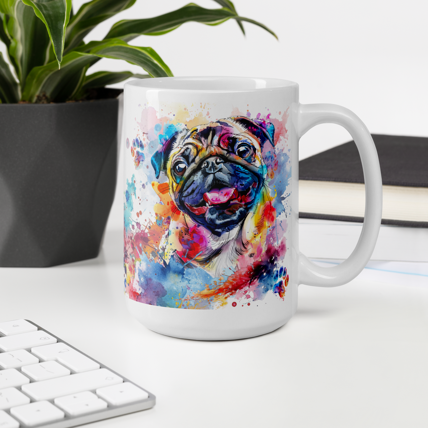 Doggone Proud Pug 15 oz Mug. A fun mug with a happy Pug dog surrounded by watercolor splashes, clouds, and paws. Mug is on a white desk with a plant book and keyboard. Great give for any dog lover or paw-rent.