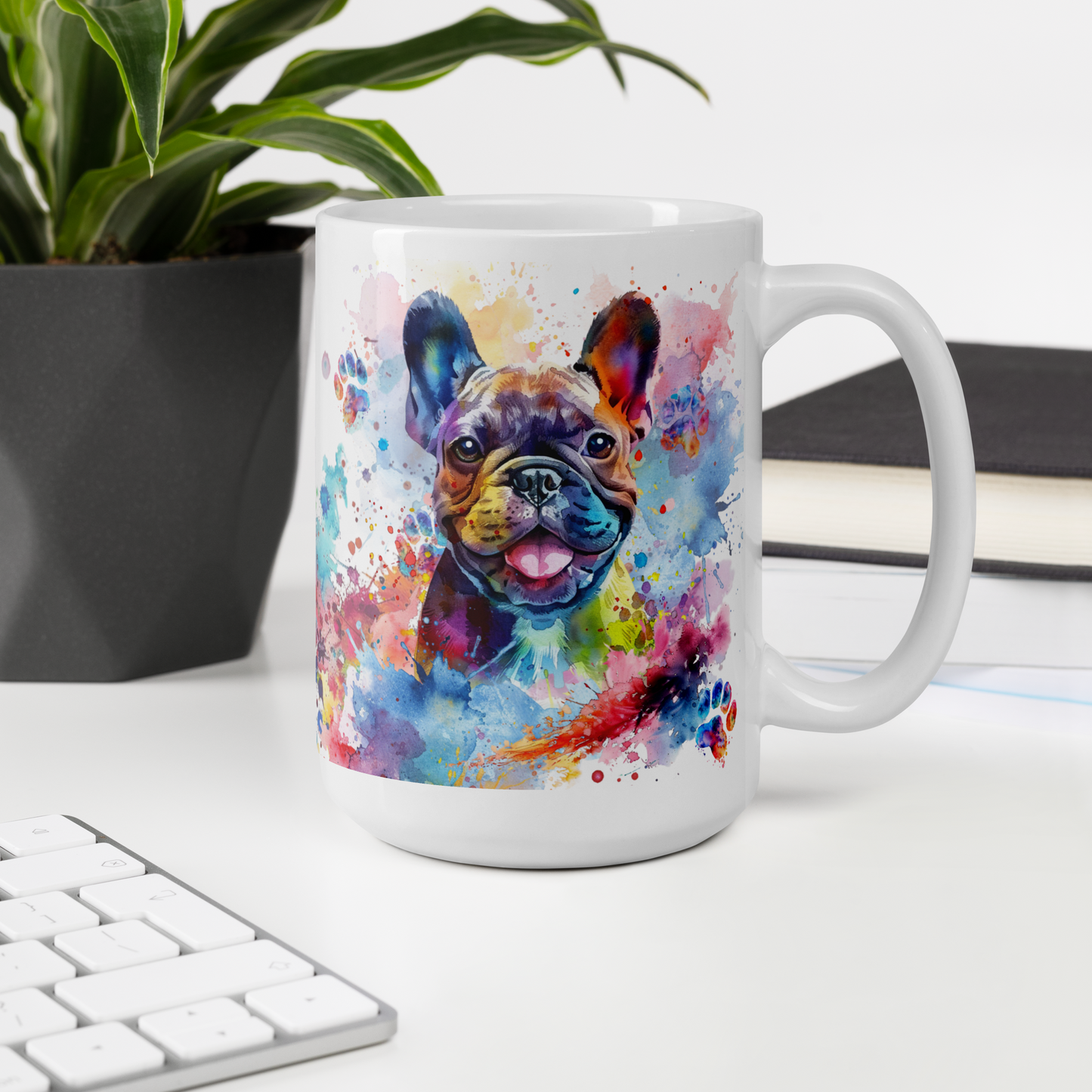 Doggone Proud Frenchie 15 oz Mug. A fun mug with a happy French Bulldog surrounded by watercolor splashes, clouds, and paws. Mug is on a white desk with a plant book and keyboard. Great give for any dog lover or paw-rent.